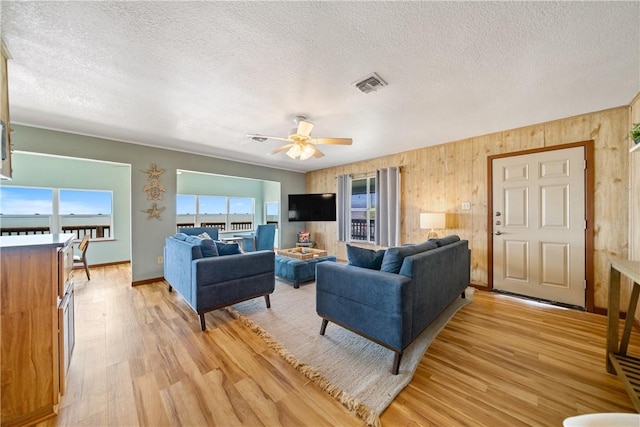 478 S County Road 1144, Riviera, TX 78379 - living area with light wood finished floors, a textured ceiling, a ceiling fan, wood walls, and baseboards