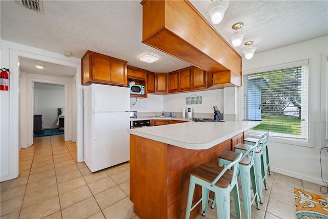 478 S County Road 1144, Riviera, TX 78379 - kitchen featuring freestanding refrigerator, light tile patterned flooring, a peninsula, a textured ceiling, and light countertops