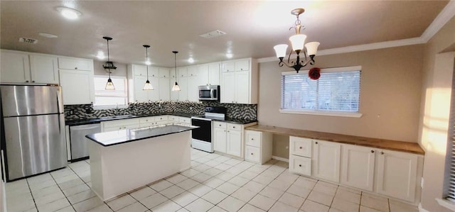 kitchen with white cabinetry, stainless steel appliances, tasteful backsplash, decorative light fixtures, and a kitchen island