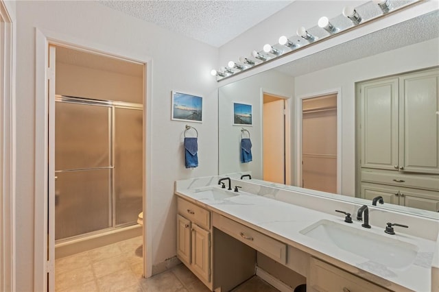 full bathroom with a shower stall, a sink, and a textured ceiling