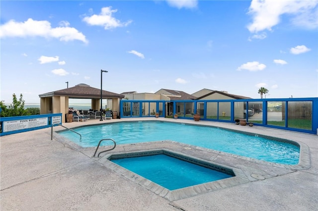 community pool with a gazebo, a hot tub, and a patio