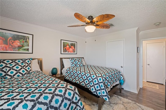 bedroom featuring wood finished floors, visible vents, and crown molding