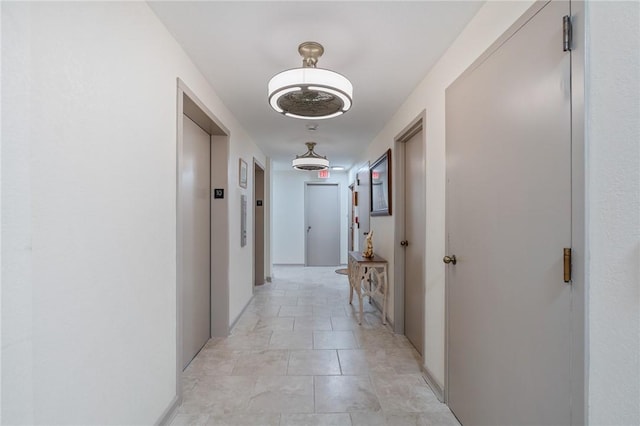 corridor with elevator and baseboards