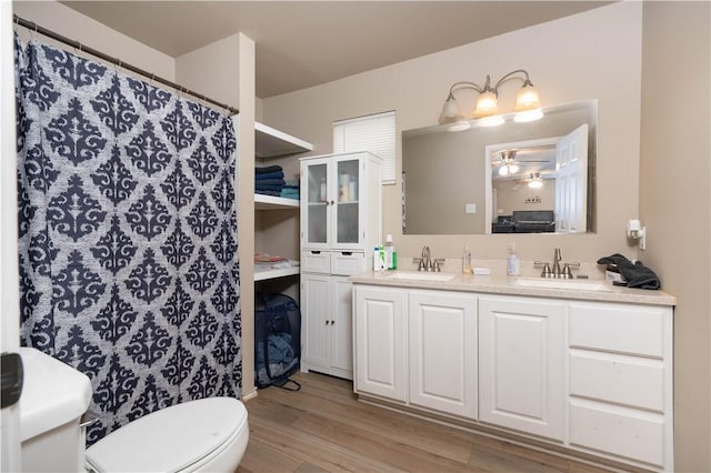 504 E Sarah St, Beeville, TX 78102 - full bath with wood finished floors, toilet, double vanity, a ceiling fan, and a shower with shower curtain