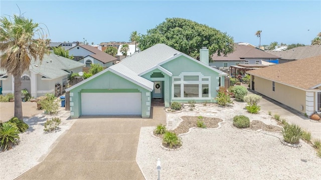15658 Cumana Dr, Corpus Christi, TX 78418 - single story home with concrete driveway, an attached garage, a residential view, a chimney, and stucco siding
