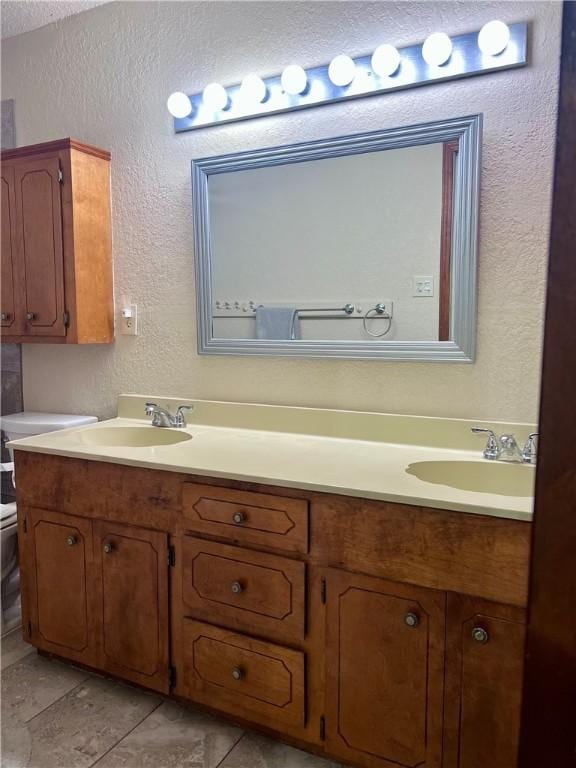 806 Dakota St, Robstown, TX 78380 - bathroom featuring a textured wall, double vanity, and tile patterned flooring