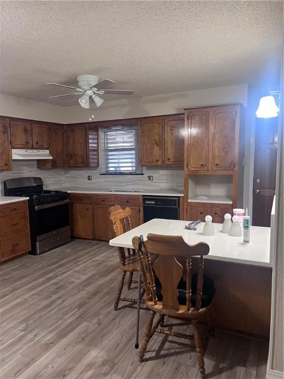 806 Dakota St, Robstown, TX 78380 - kitchen featuring gas stove, under cabinet range hood, dishwasher, a textured ceiling, and light wood-style floors