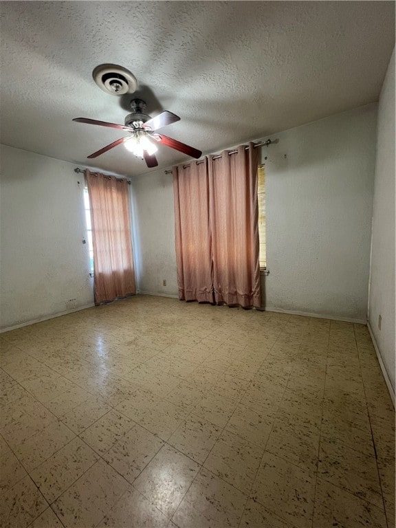 empty room with ceiling fan and a textured ceiling