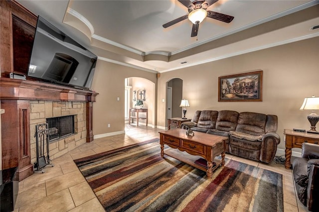 tiled living room featuring ceiling fan, ornamental molding, a raised ceiling, and a fireplace