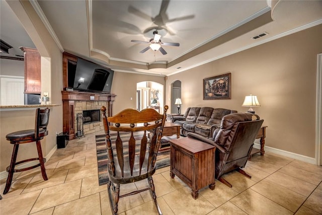 living room with crown molding, light tile patterned floors, ceiling fan, and a tray ceiling