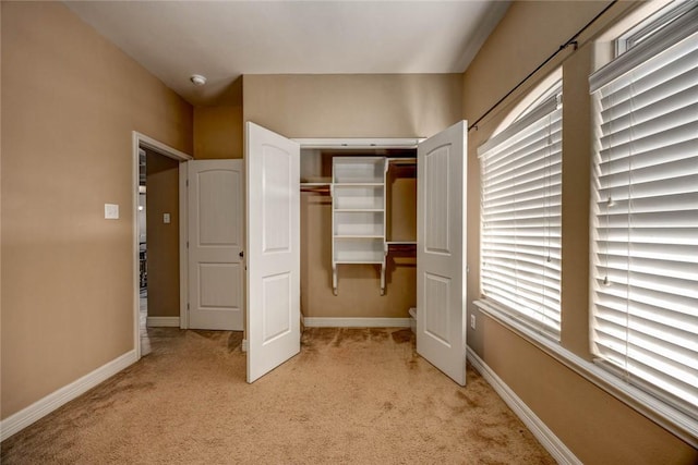 unfurnished bedroom featuring light carpet, a closet, and multiple windows