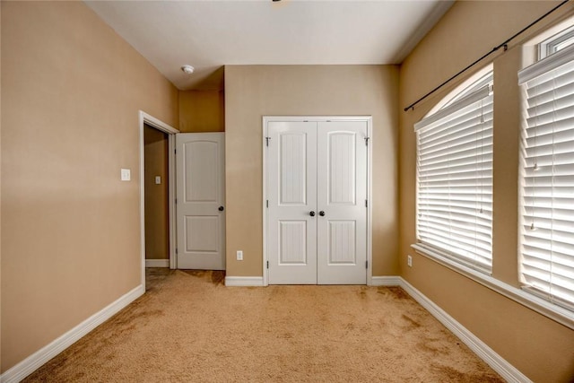 unfurnished bedroom with light colored carpet and a closet