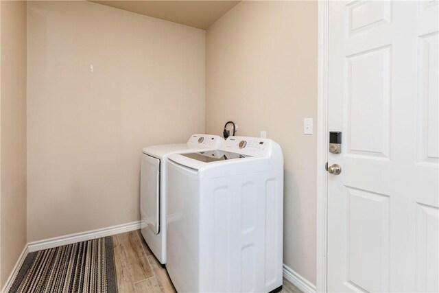 6766 Mikayla St, Corpus Christi, TX 78413 - clothes washing area with washing machine and dryer, baseboards, and light wood finished floors