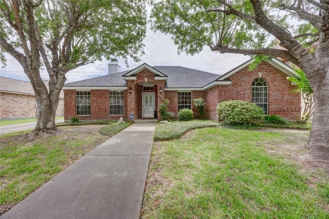 8006 Etienne Dr, Corpus Christi, TX 78414 - view of front of home with brick siding, a chimney, a front yard, and a shingled roof