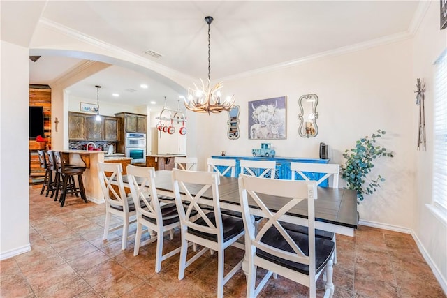 dining space with arched walkways, crown molding, and baseboards