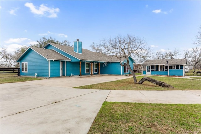 ranch-style house featuring a chimney, fence, concrete driveway, and a front yard