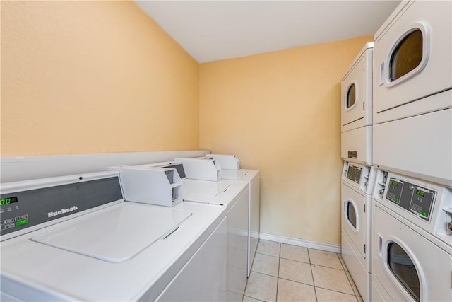 community laundry room featuring stacked washer / drying machine, washing machine and dryer, baseboards, and light tile patterned flooring