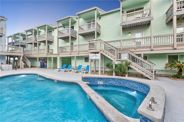 outdoor pool featuring stairway, a patio, and a hot tub