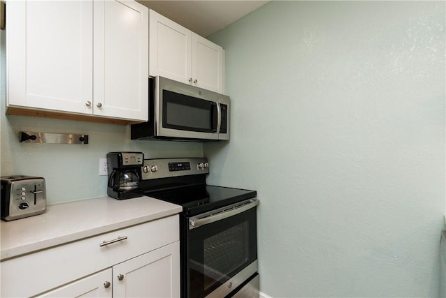 kitchen with stainless steel appliances, white cabinets, and light countertops