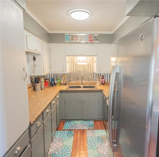 kitchen with stainless steel refrigerator, white cabinetry, sink, gray cabinetry, and crown molding