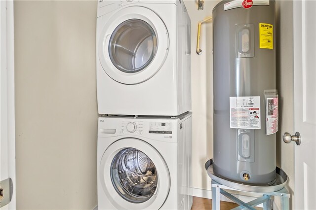 clothes washing area featuring electric water heater and stacked washer and clothes dryer