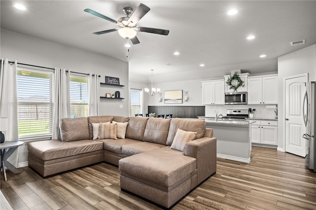 2689 Everly Ln, Corpus Christi, TX 78415 - living room featuring wood finished floors, recessed lighting, a ceiling fan, and a chandelier