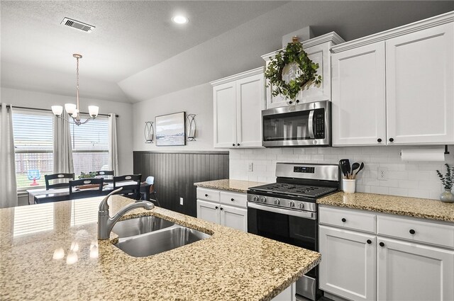 2689 Everly Ln, Corpus Christi, TX 78415 - kitchen featuring stainless steel appliances, a sink, vaulted ceiling, white cabinetry, and a chandelier