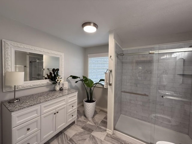 bathroom featuring a shower with door and vanity