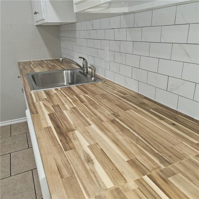 4749 Mokry Dr, Corpus Christi, TX 78415 - kitchen with a sink, butcher block countertops, decorative backsplash, white cabinets, and tile patterned floors