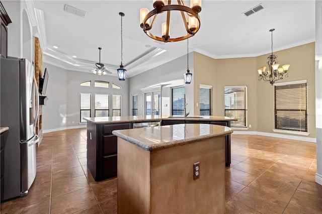 kitchen featuring a raised ceiling, stainless steel appliances, pendant lighting, plenty of natural light, and a kitchen island