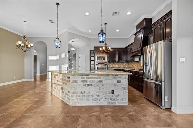 kitchen with a kitchen island with sink, stainless steel appliances, sink, dark brown cabinets, and decorative light fixtures