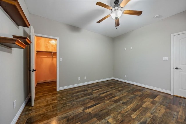 unfurnished bedroom featuring dark hardwood / wood-style floors, a closet, ceiling fan, and a spacious closet