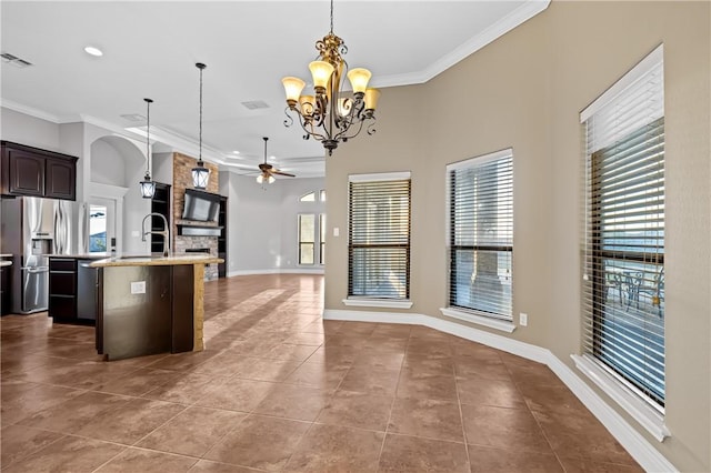 kitchen with appliances with stainless steel finishes, hanging light fixtures, light tile patterned floors, dark brown cabinetry, and ceiling fan with notable chandelier