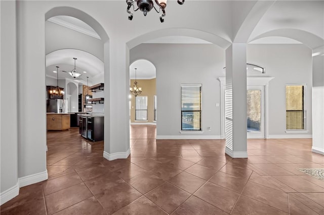 interior space featuring ceiling fan with notable chandelier, dark tile patterned flooring, a towering ceiling, and ornamental molding