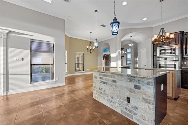 kitchen with stainless steel appliances, dark brown cabinets, decorative light fixtures, and a kitchen island with sink