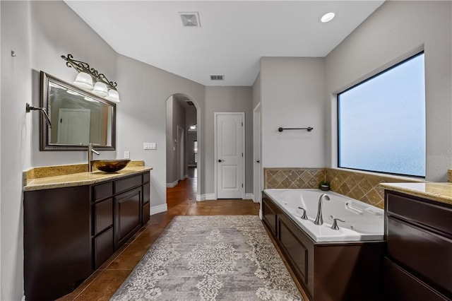 bathroom with tile patterned flooring, a tub to relax in, and vanity