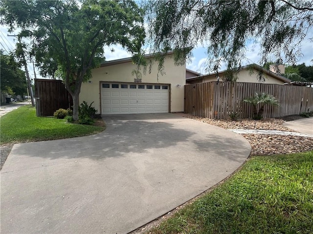 1504 Morningside Dr, Alice, TX 78332 - view of side of property featuring fence, concrete driveway, a garage, and stucco siding