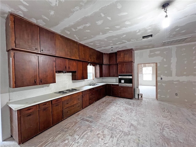 kitchen with electric stovetop, stainless steel oven, sink, and dark brown cabinetry