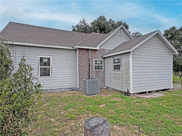 rear view of property featuring a yard and cooling unit