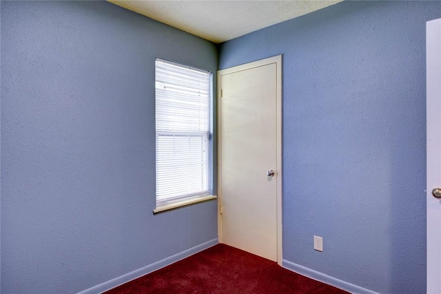 unfurnished room featuring dark colored carpet