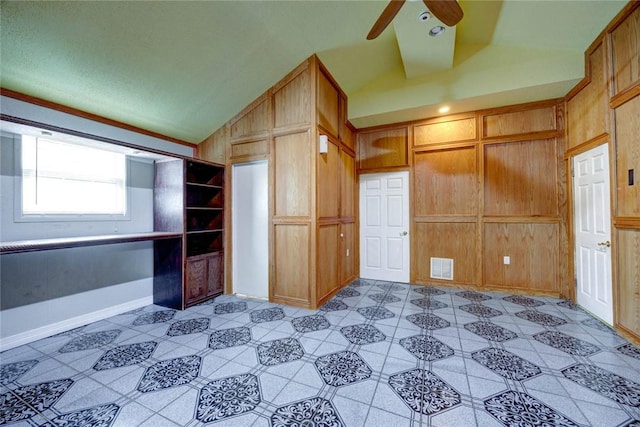 interior space with a closet, ceiling fan, wooden walls, and lofted ceiling