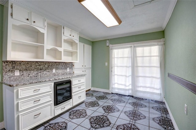 kitchen with white cabinets, light stone counters, and crown molding