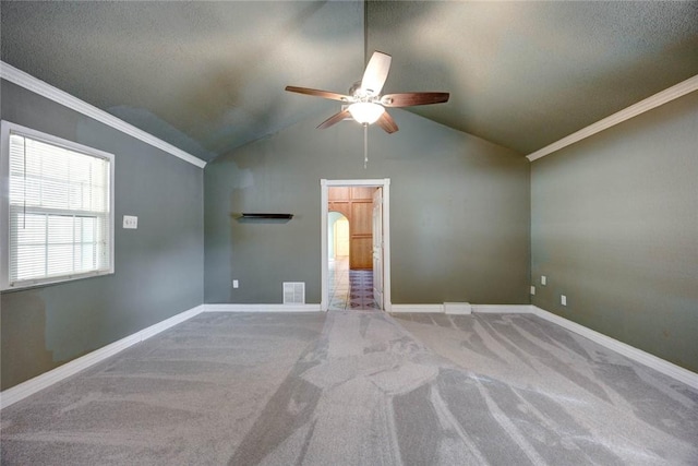 carpeted spare room with vaulted ceiling, ceiling fan, and ornamental molding