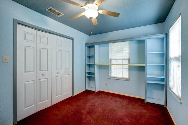 unfurnished bedroom with dark carpet, a closet, and ceiling fan