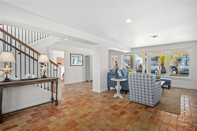 living area with brick floor, recessed lighting, visible vents, baseboards, and stairs