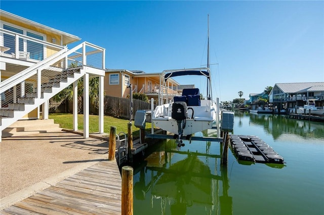 dock area featuring a water view, fence, boat lift, and stairs