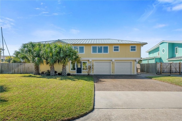 view of front of home featuring aphalt driveway, an attached garage, a standing seam roof, fence, and a front lawn