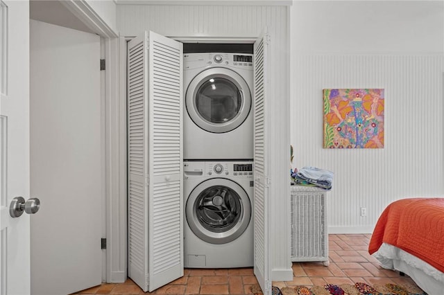 washroom with baseboards, laundry area, and stacked washer / drying machine