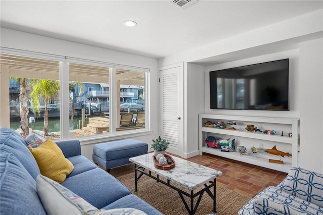 living room featuring brick floor, baseboards, visible vents, and recessed lighting