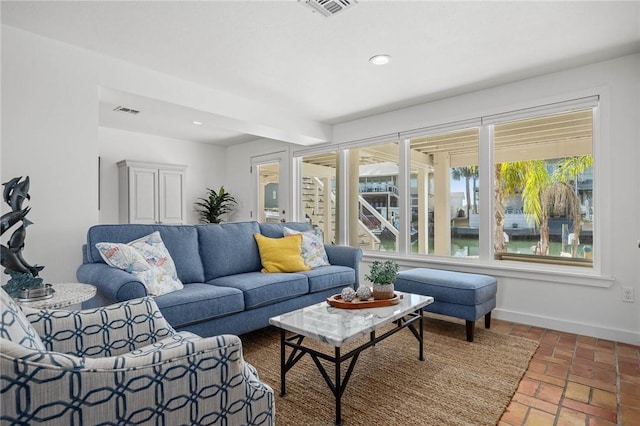 living area with recessed lighting, brick floor, visible vents, and baseboards